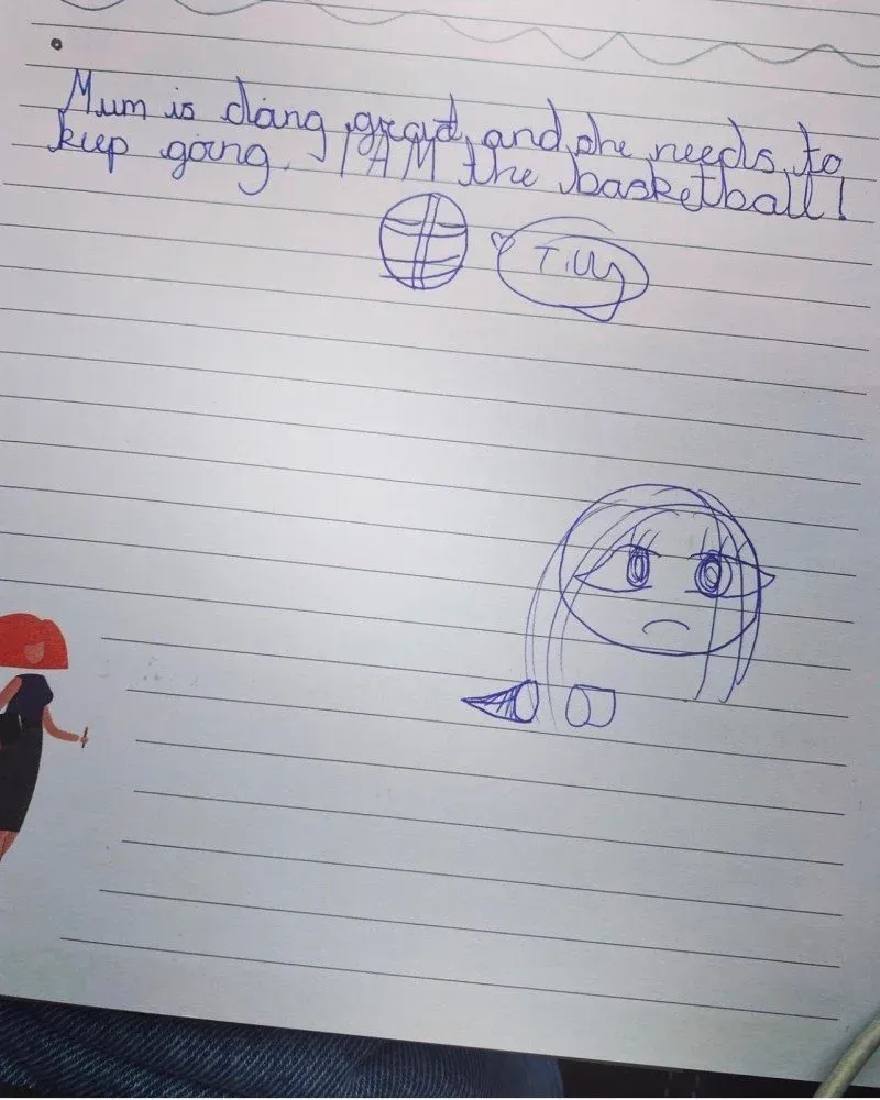 A child’s handwritten note on lined paper reading ‘Mum is doing great, and she needs to keep going. I AM the basketball!’, signed Tilly, with a drawing of a basketball and a face.