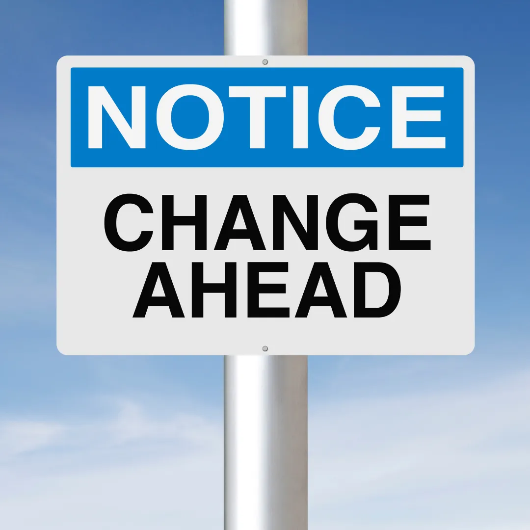 A roadside sign against a blue sky reading 'Notice: change ahead'.